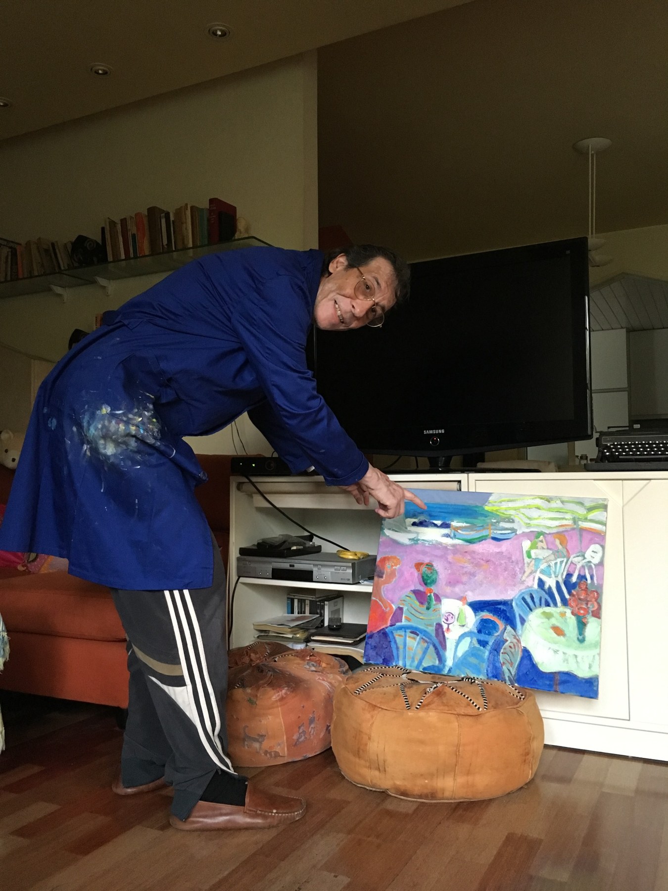 Jesús trabajando con bata azul junto a sus pinturas