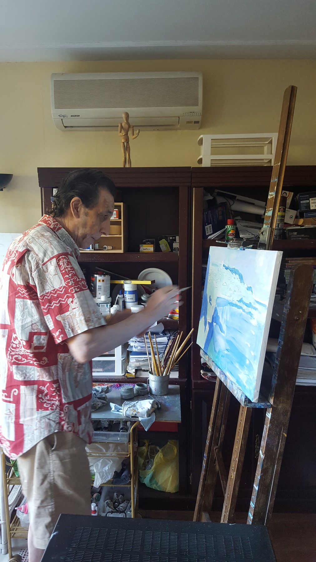 Jesús pintando en su estudio con su camisa roja estampada